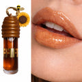 Gloss labial marrom dourado com embalagem temática de abelha e girassol e efeito brilhante nos lábios.
